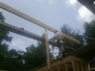 Carpenter setting a ridge beam over a new addition frame — Ice Dam Removal by Roofing Brothers in Rock River