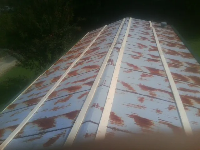 Rusted metal roof panels with new wood purlins before replacement — Storm Damage Roof Repair in Rock River by Roofing Brothers