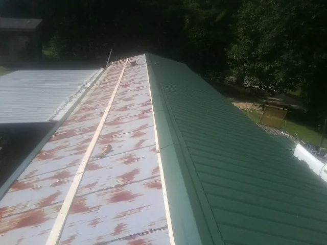 Old rusted panels beside newly installed green metal roofing — Wind Damage Roof Repair by Roofing Brothers in Rock River