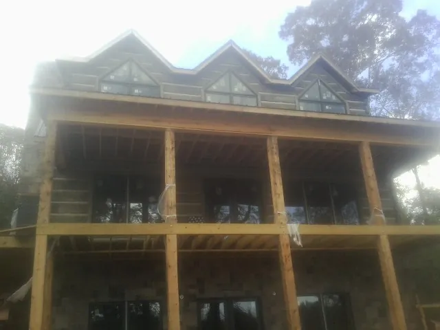 Dormers and porch framing on a large log home under construction — Roof Coating work by our crew in Rock River
