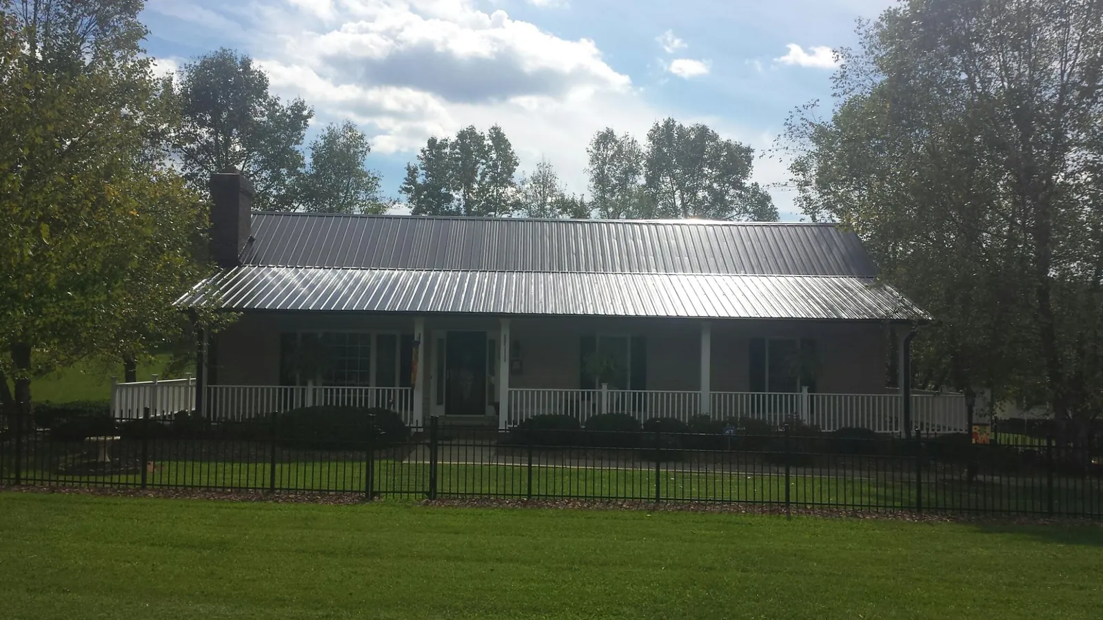 Gray metal roof on a brick ranch with a full width front porch — Gutter Guard Installation work by our crew in Rock River