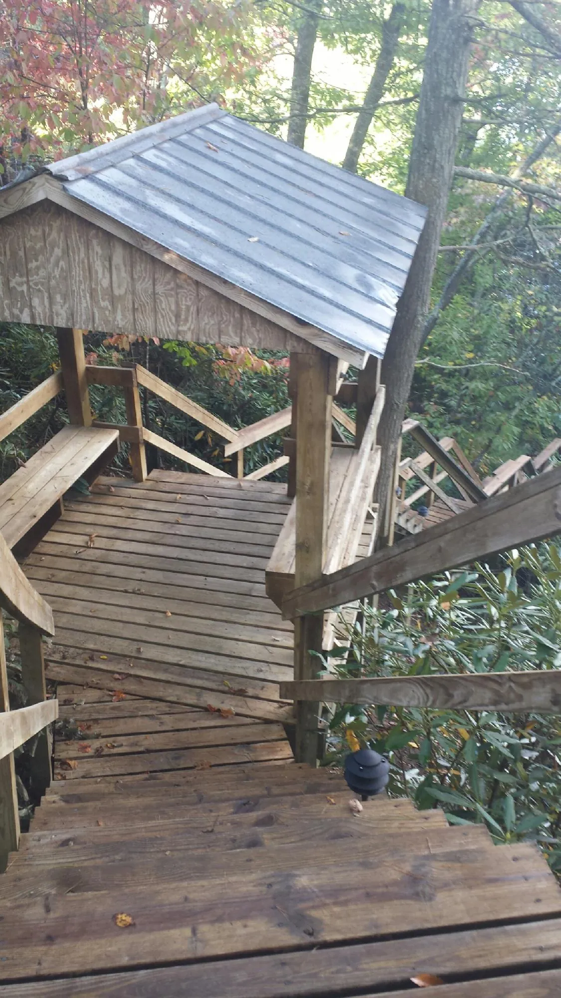 Metal roofed shelter over wooden steps on a wooded walkway — Skylight Repair & Installation work by our crew in Rock River
