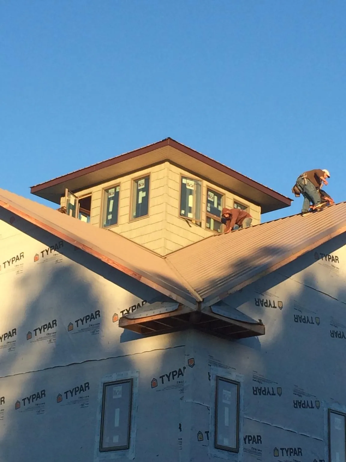 Roofers working around a rooftop cupola on a new metal roof at sunset — Roof Waterproofing in Rock River by Roofing Brothers